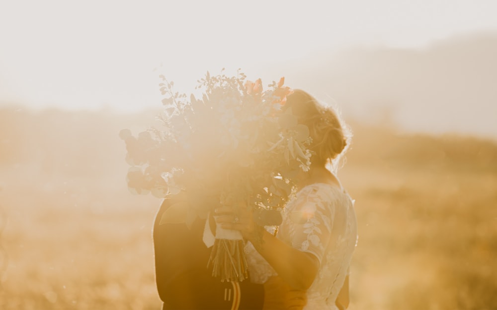 a woman holding a bouquet of flowers in a field