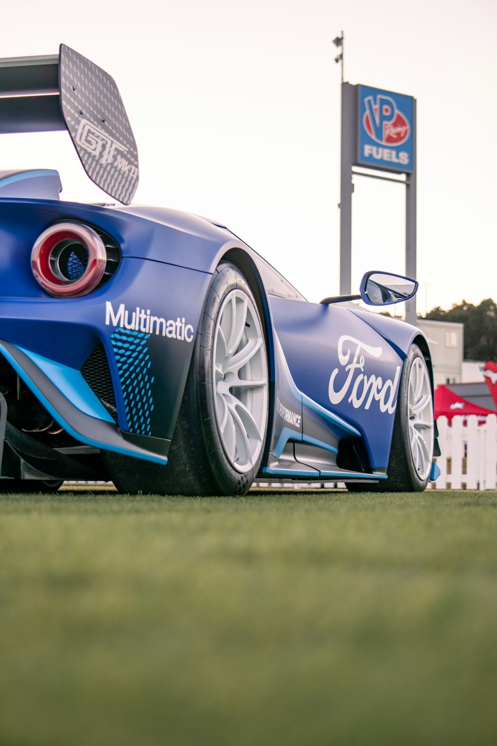 a blue sports car parked on top of a lush green field