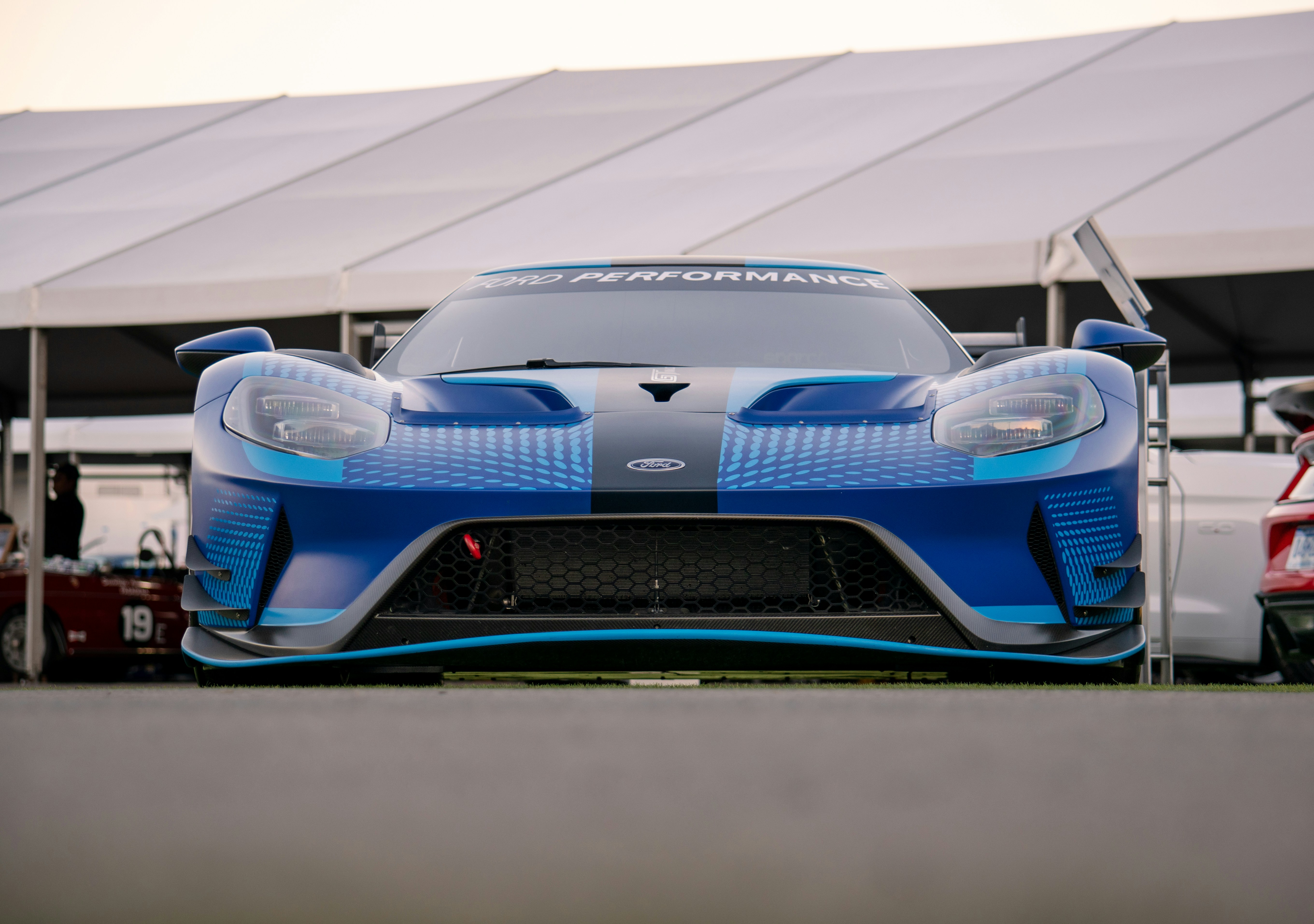 a blue sports car parked in front of a tent