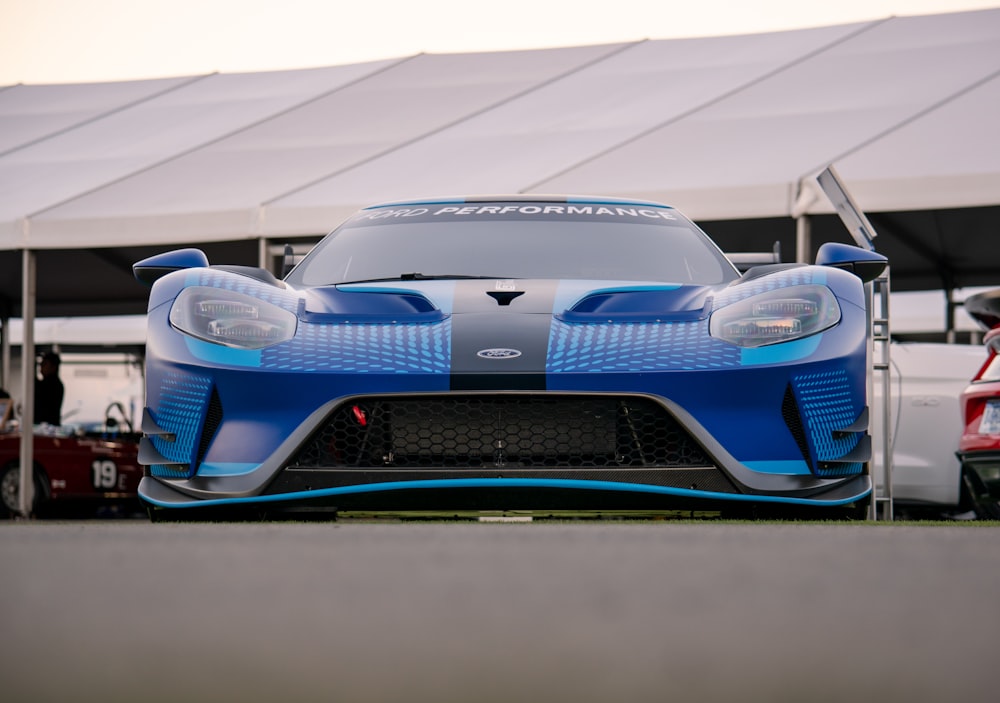 a blue sports car parked in front of a tent