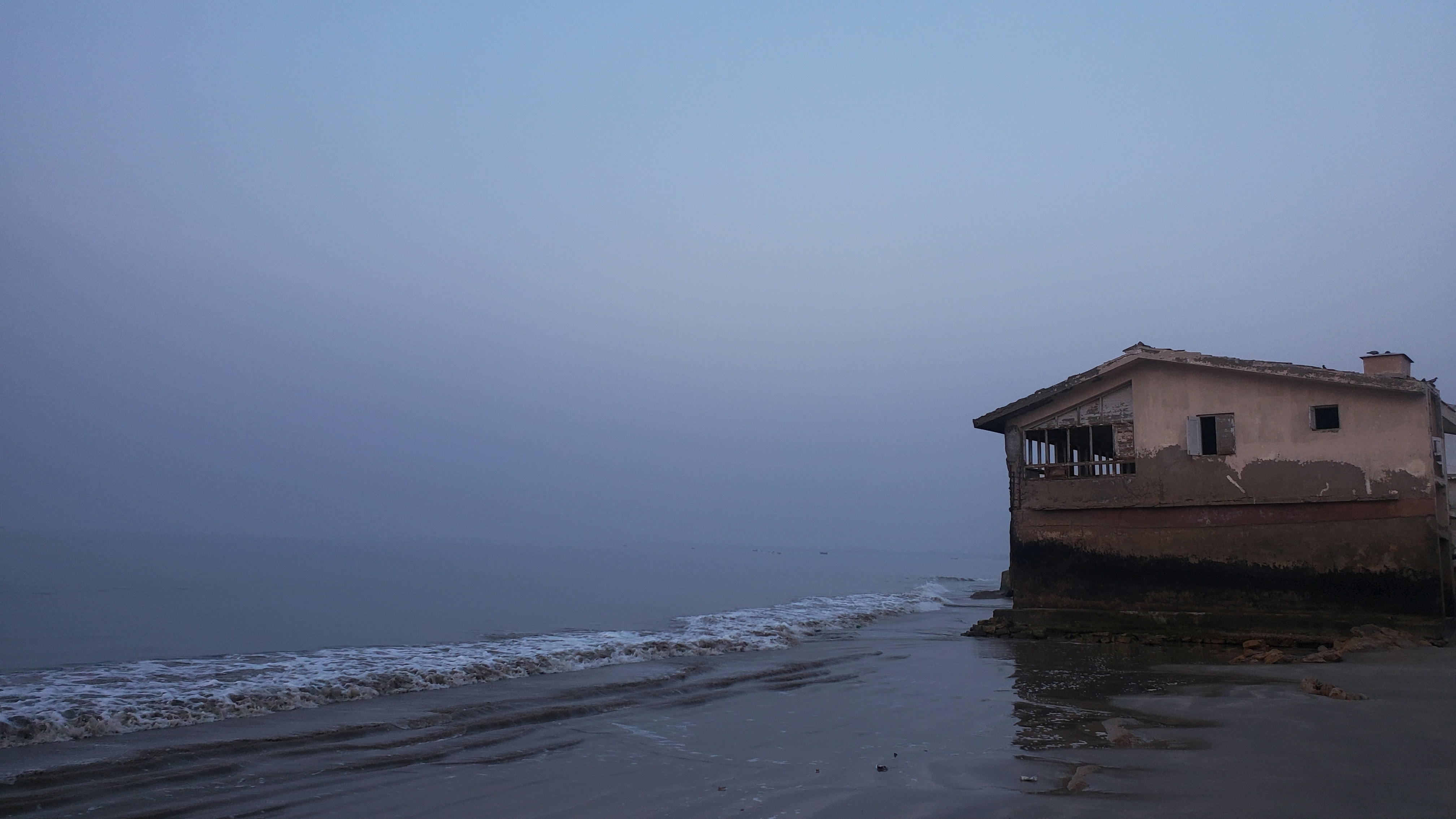a house sitting on top of a beach next to the ocean