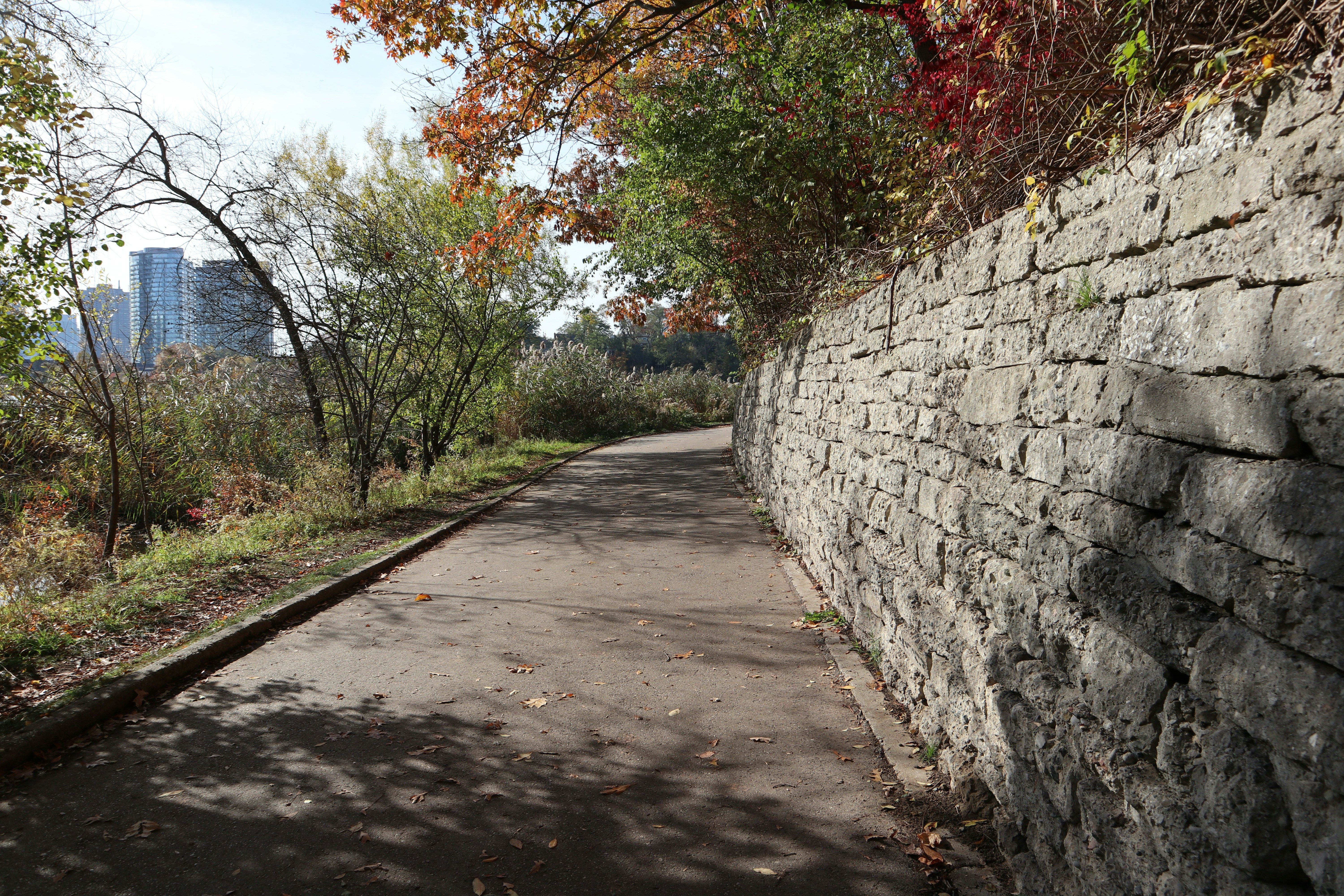 a stone wall next to a paved road