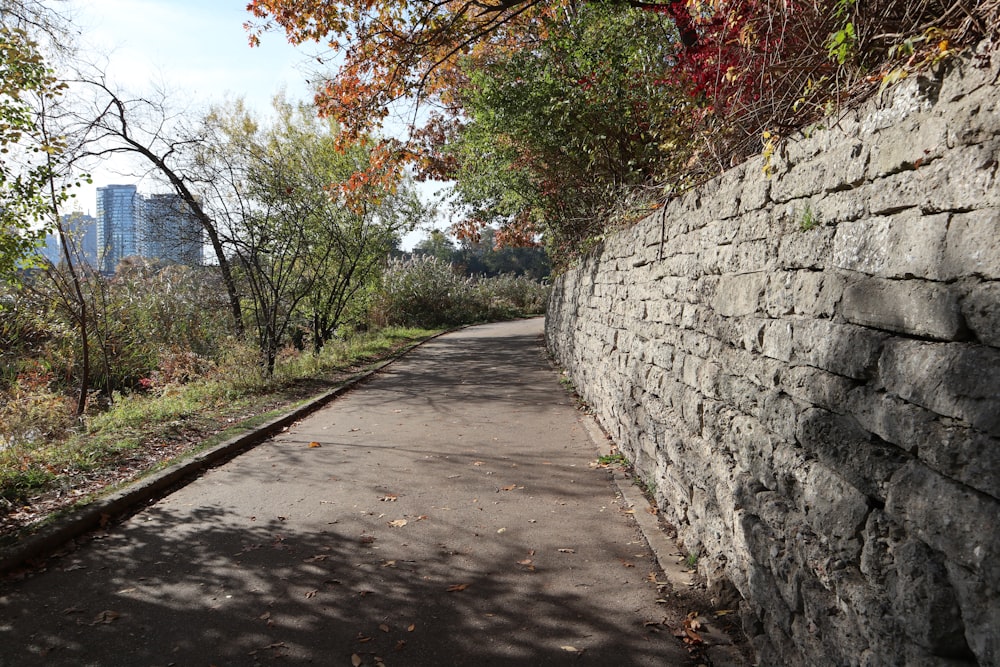 a stone wall next to a paved road