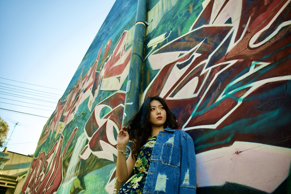a woman leaning against a wall with graffiti on it