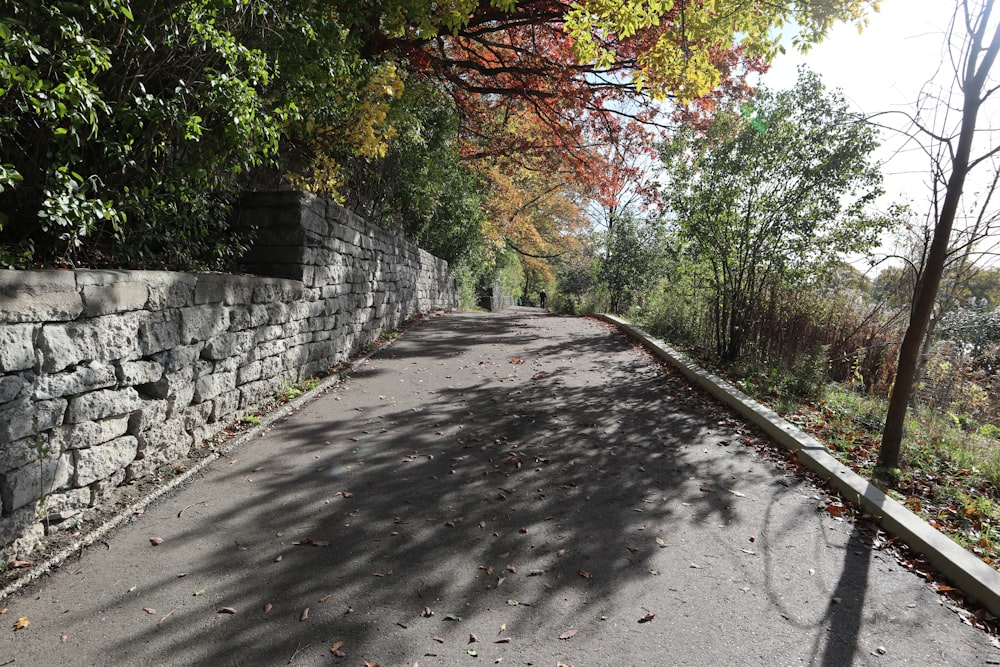 a paved road with a stone wall next to it