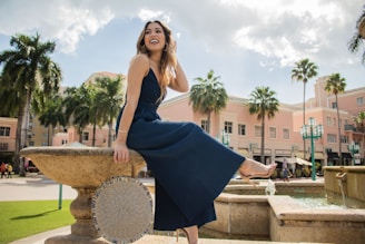 a woman in a blue dress sitting on a fountain
