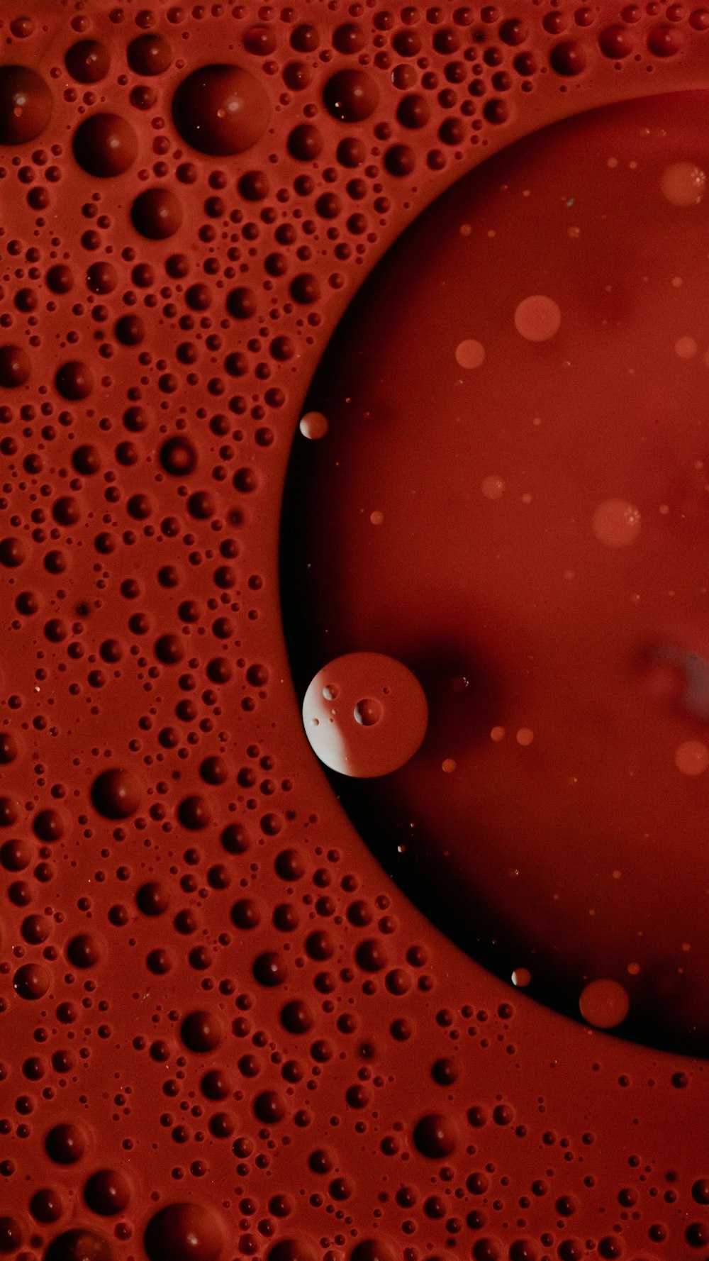 a close up of a red substance with drops of water