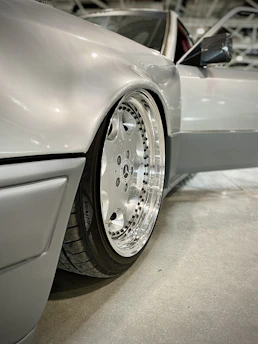 Close-up of a shiny, freshly polished car alloy wheel reflecting light in a modern workshop.