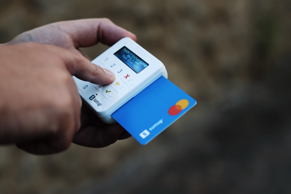 una mano sosteniendo una tarjeta de crédito y un teléfono celular