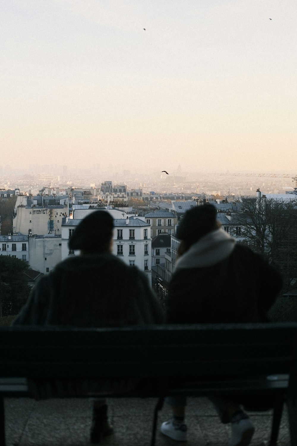 two people sitting on a bench overlooking a city