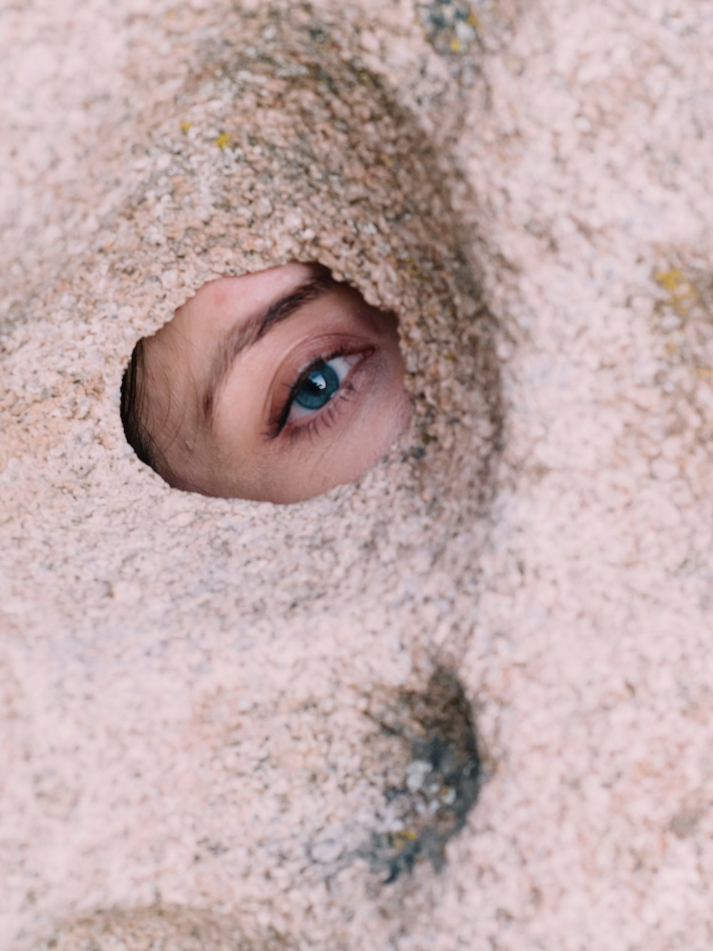 a close up of a person's eye through a hole in the sand