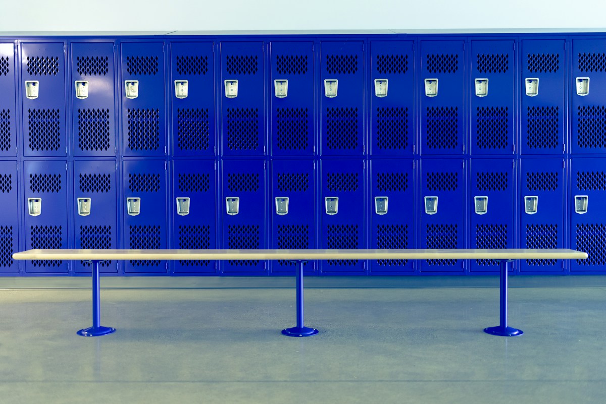 A wooden bench sits empty against a blue wall, suggesting a quiet space for team bonding questions and athlete icebreakers.