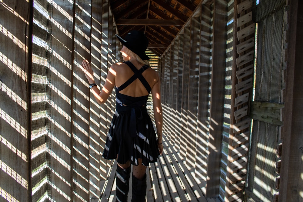 a woman in a black dress is standing on a bridge