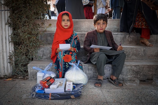 a boy and a girl sitting on the steps of a building