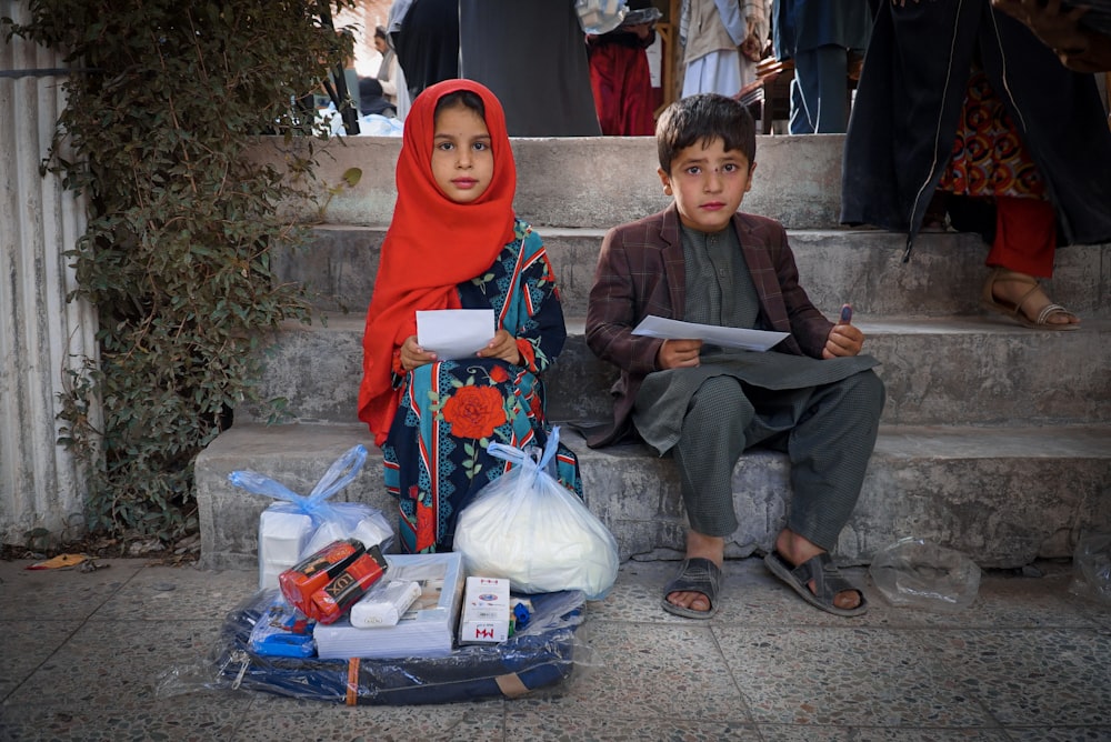 a boy and a girl sitting on the steps of a building