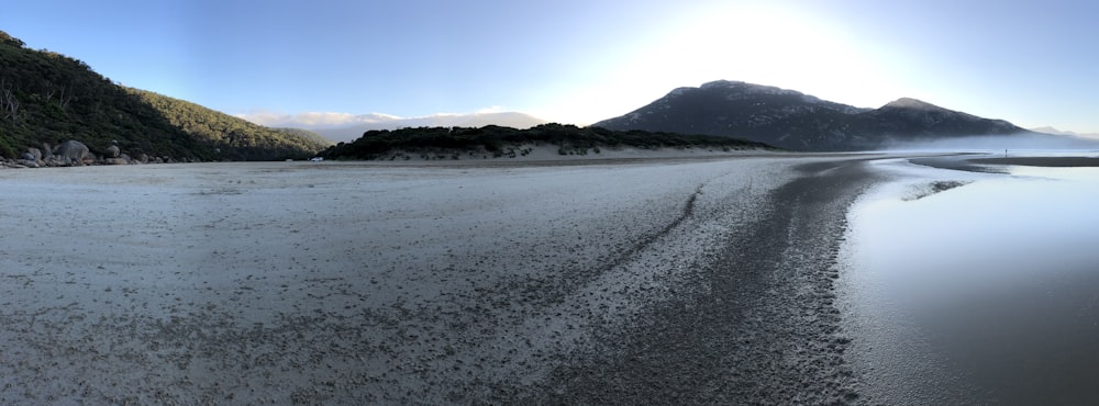 a sandy beach with mountains in the background