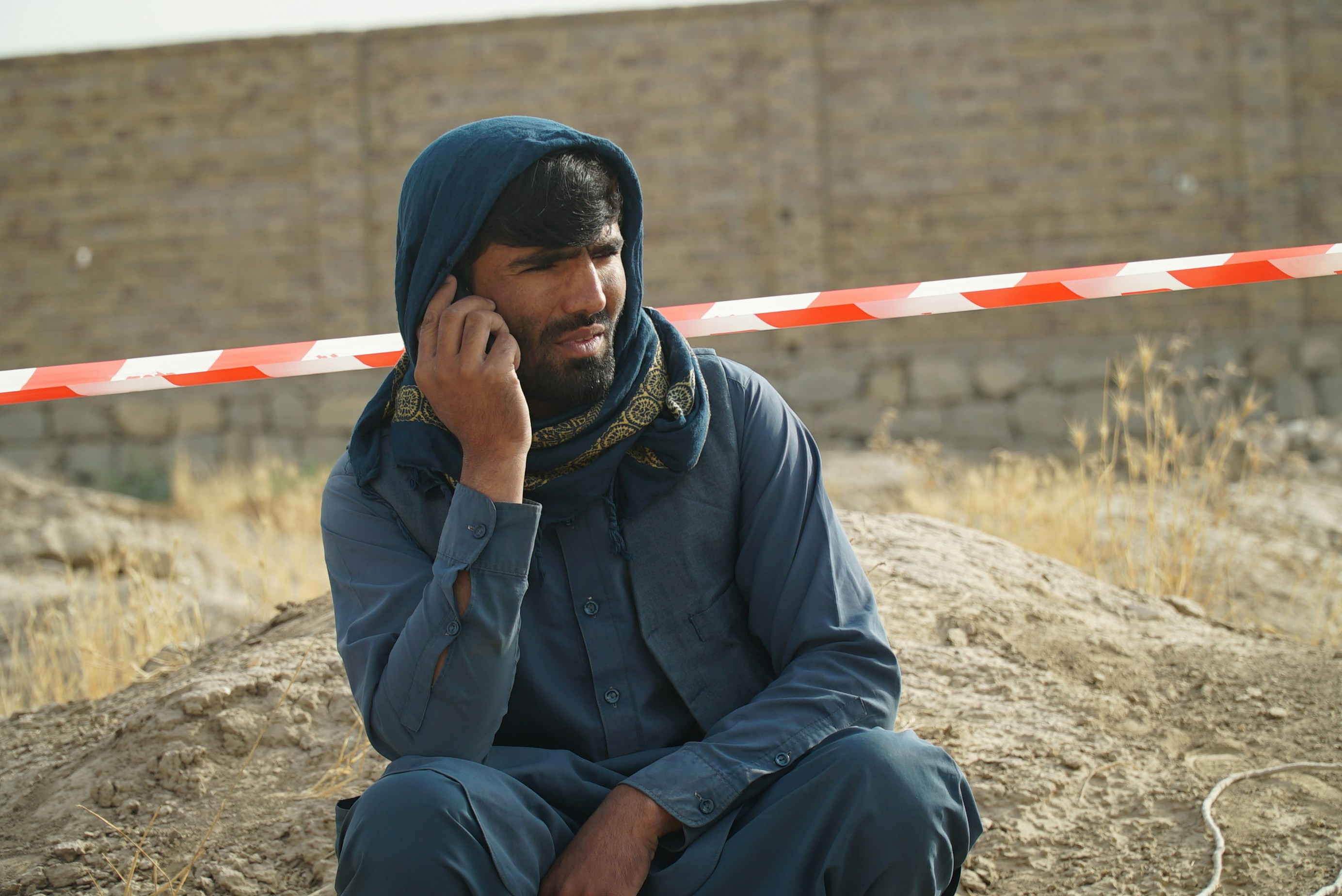 Un uomo seduto a terra che parla al cellulare