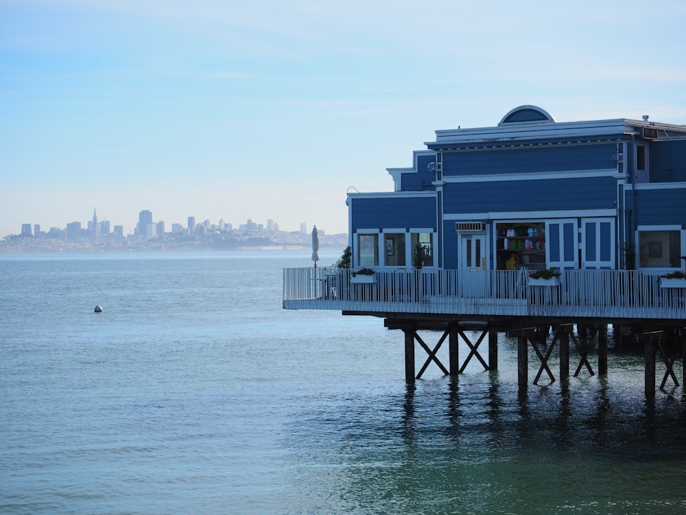 a blue building sitting on top of a pier next to the ocean