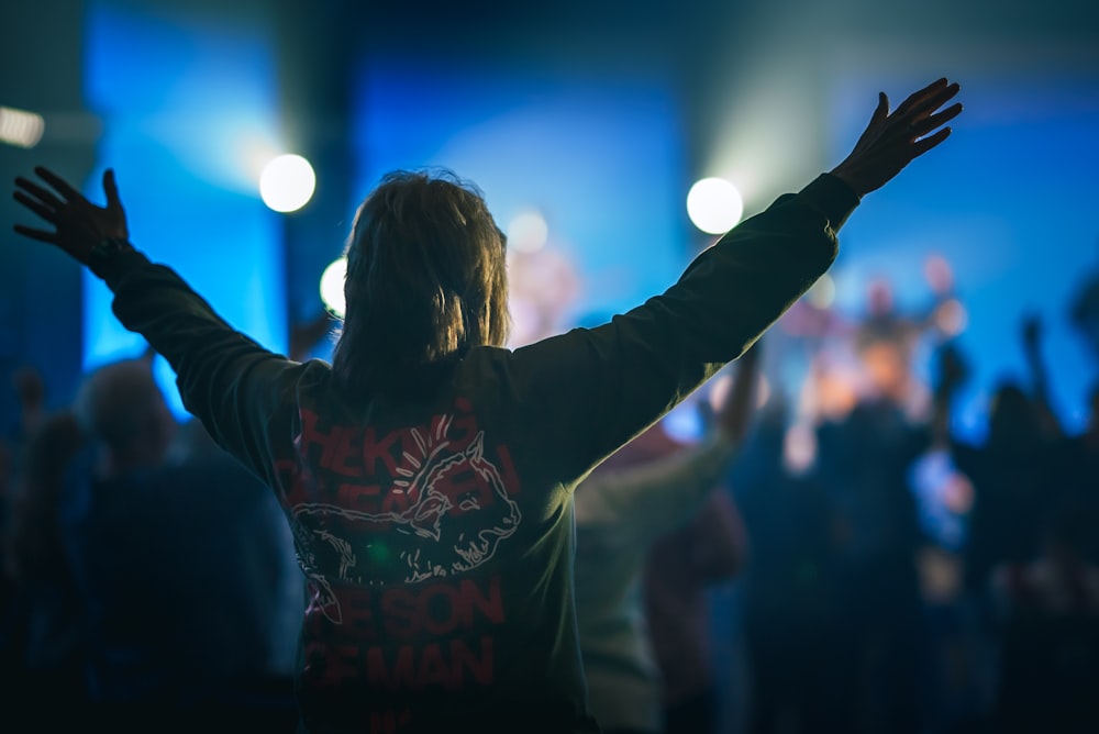 a woman with her arms up in the air at a concert