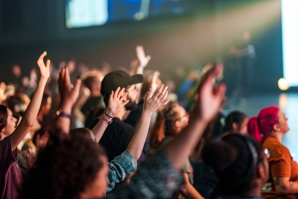 a crowd of people with their hands in the air