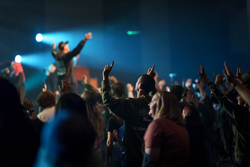 a crowd of people at a concert raising their hands in the air