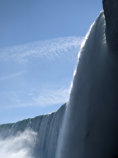 A breathtaking view of Niagara Falls cascading with mist rising under a clear blue sky.