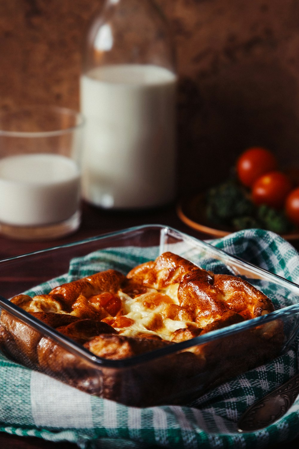 a dish of food on a table next to a glass of milk