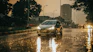 a car driving down a rain soaked street