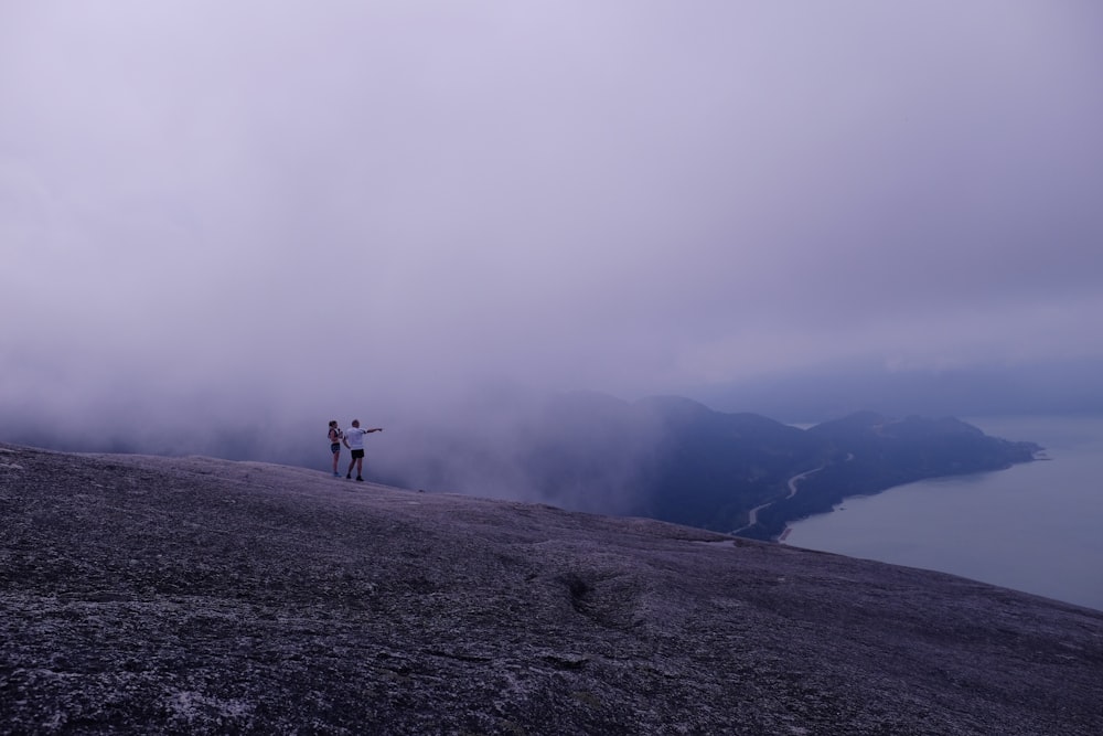 Un par de personas de pie en la cima de una montaña