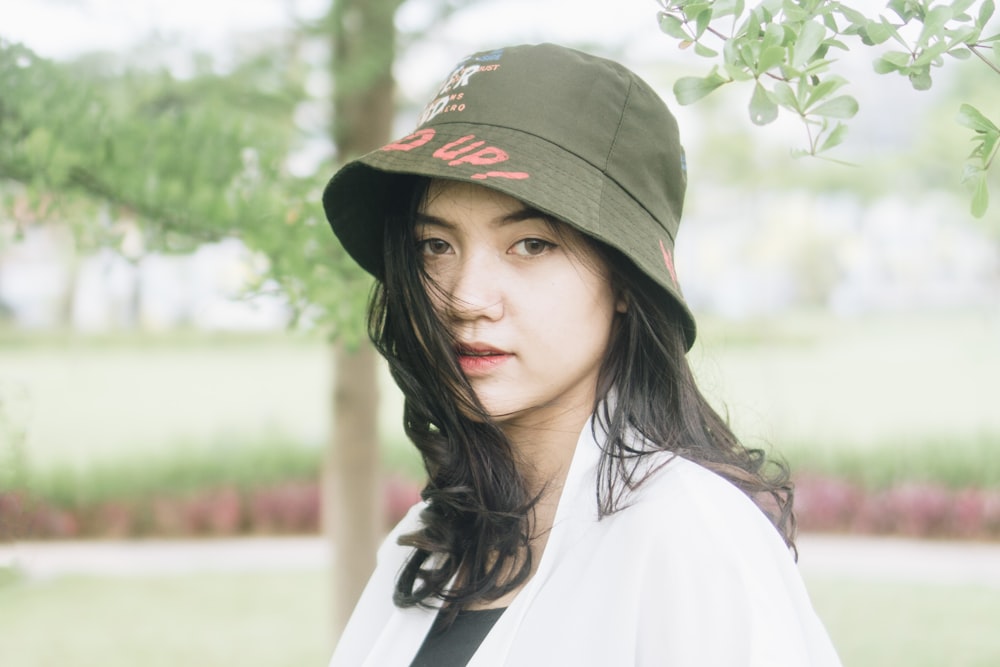 a woman wearing a hat standing under a tree