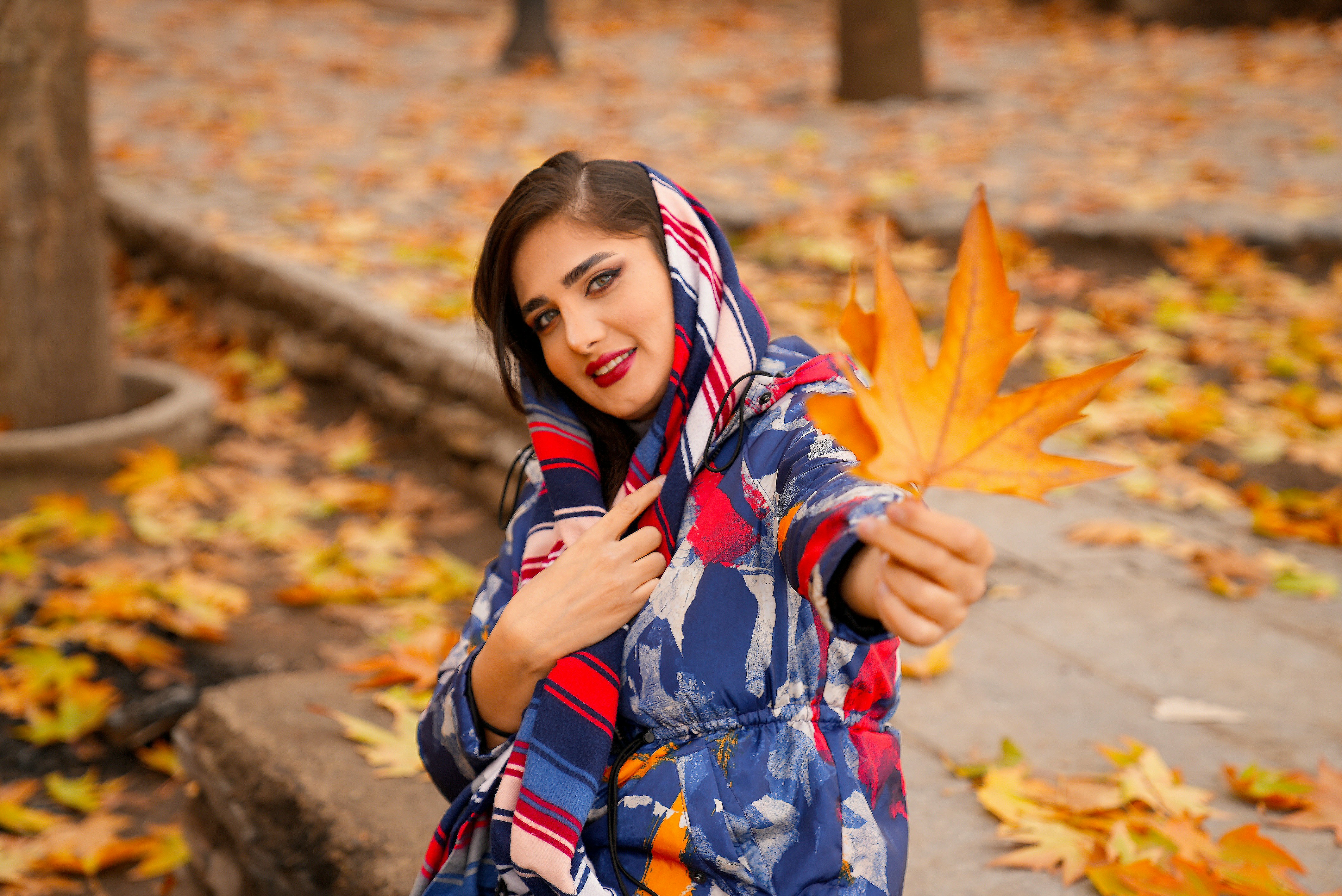 Beautiful girl in autumn nature and posing  with Leaves in hand 