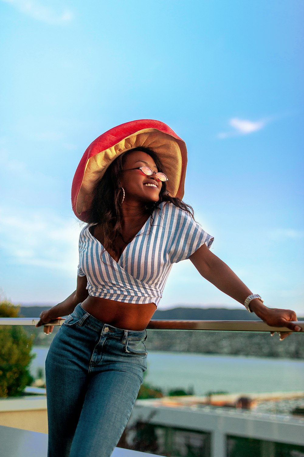 a woman in a striped shirt and hat leaning on a rail