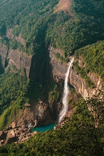 a waterfall in the middle of a lush green valley
