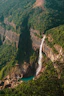 a waterfall in the middle of a lush green valley