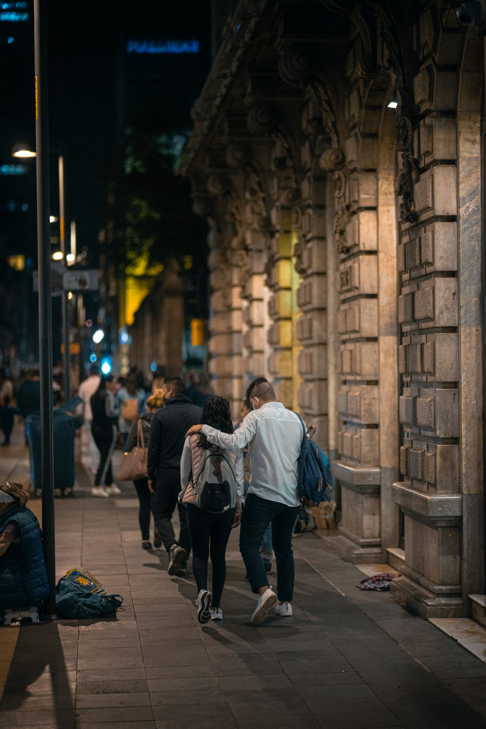 un groupe de personnes marchant dans une rue la nuit