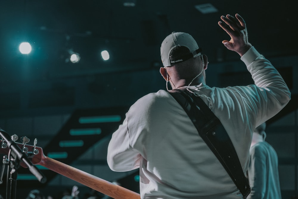 um homem com um boné de beisebol e suspensórios segurando uma guitarra