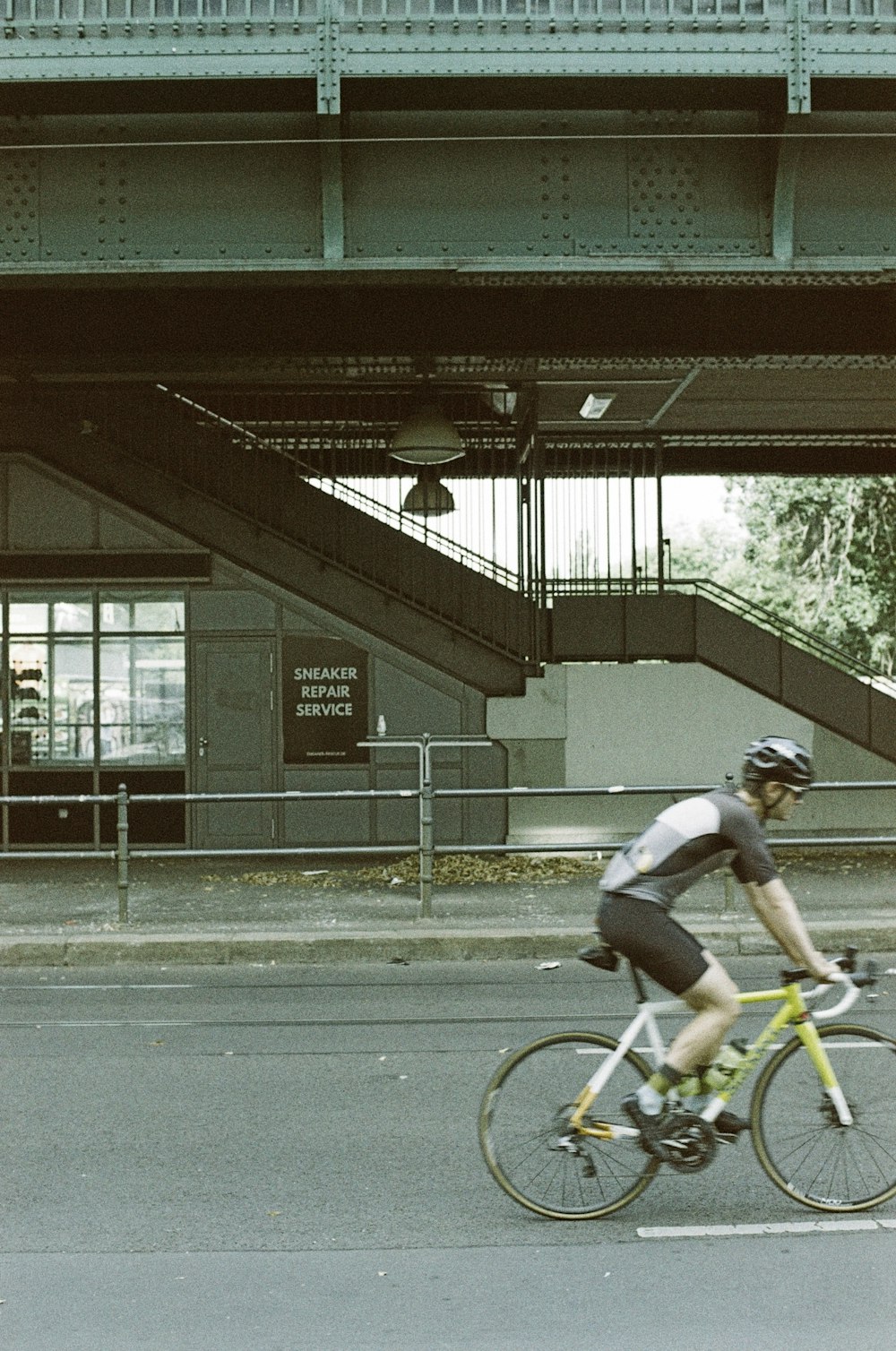 a man riding a bike down a street under a bridge