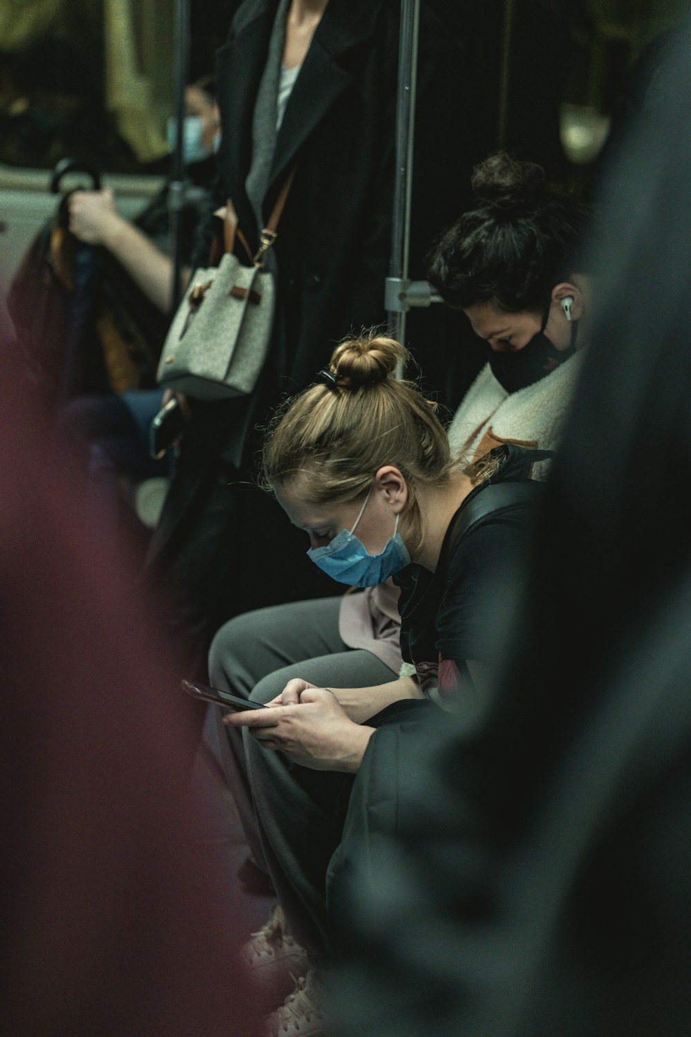 a woman sitting on a subway looking at her phone