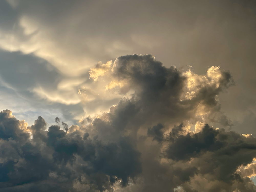 a plane flying through a cloudy sky on a sunny day