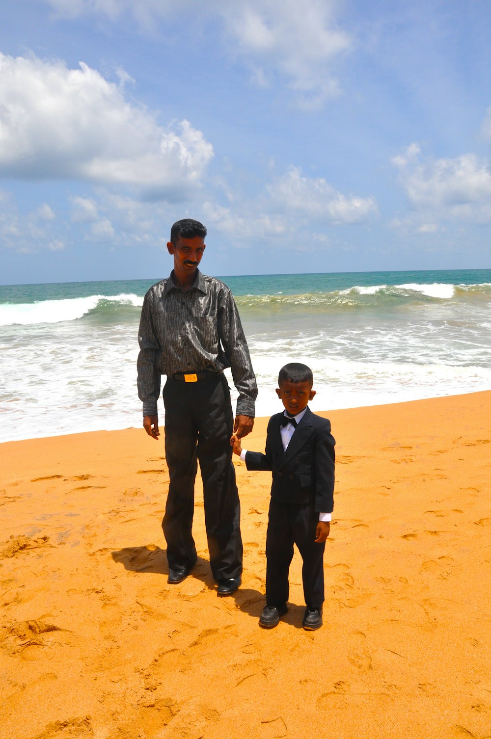 a man standing next to a little boy on a beach