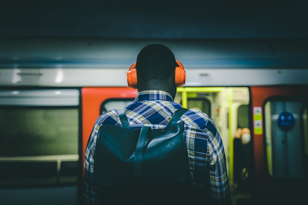 a man with headphones standing in front of a train