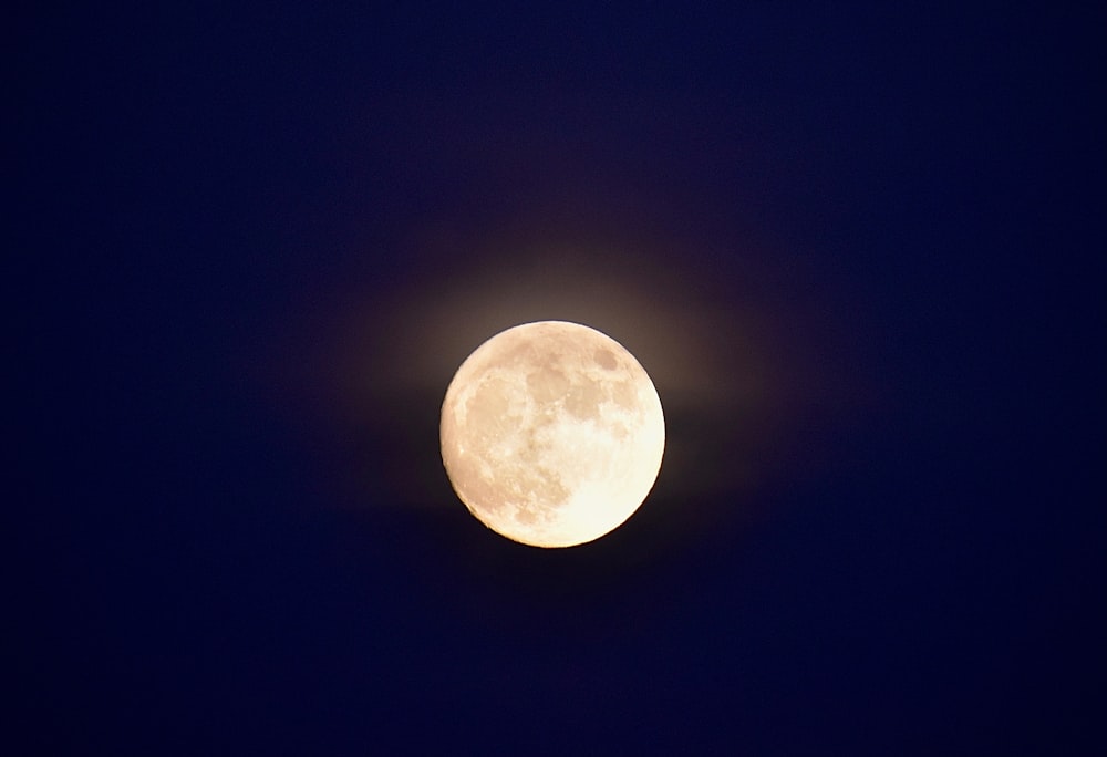 a full moon is seen in the dark sky