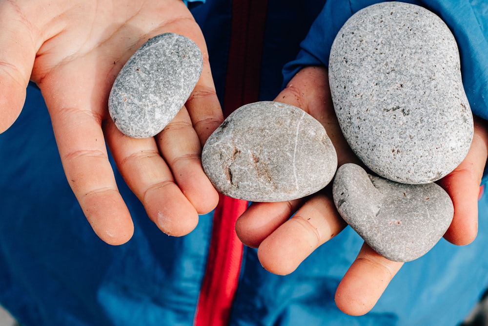 a person holding three rocks in their hands