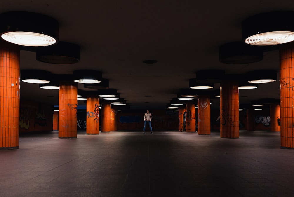 a person standing in a large room with orange pillars
