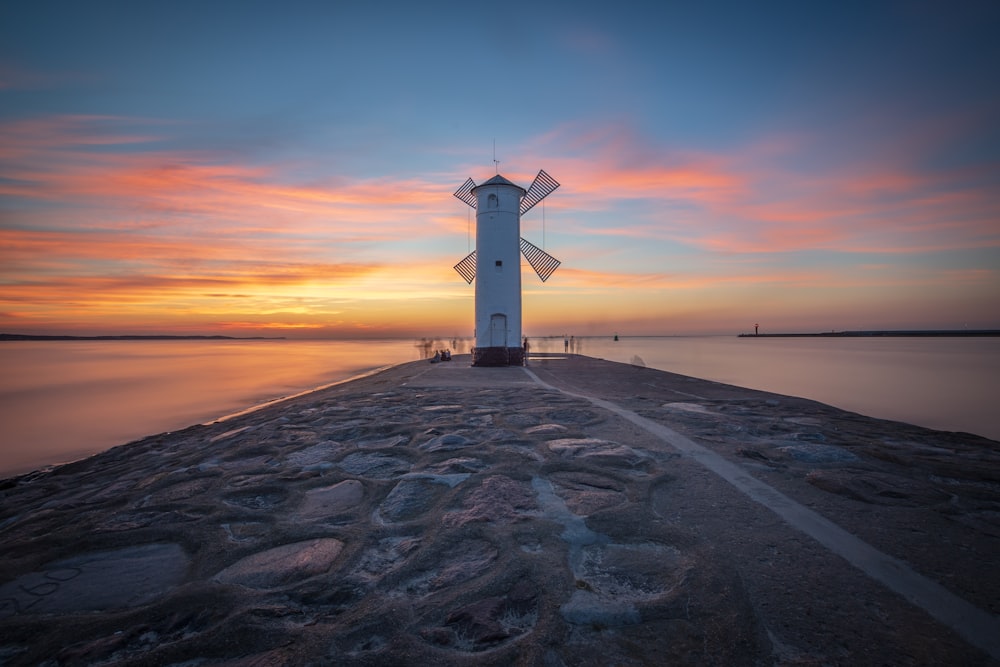 a windmill sitting on top of a pier next to a body of water