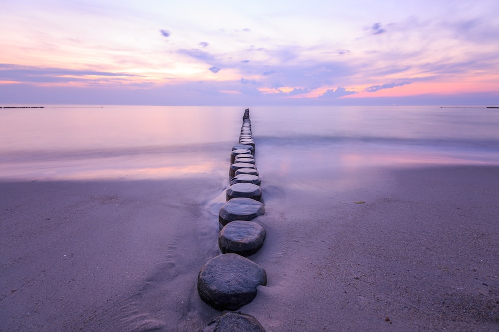 a row of rocks sitting on top of a sandy beach