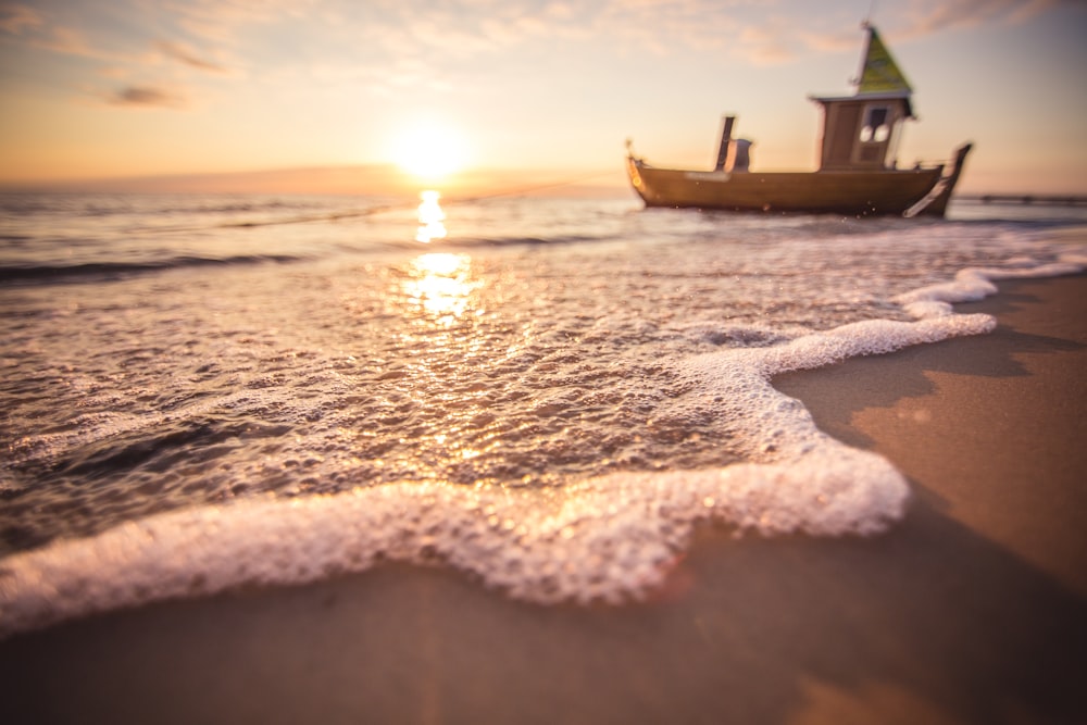 a boat is sitting on the beach at sunset