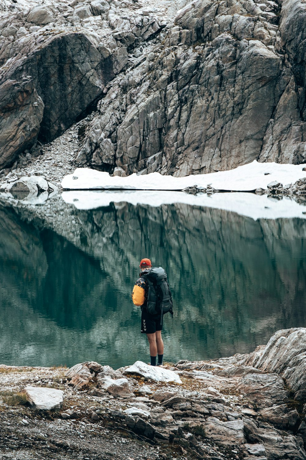 a man with a backpack standing on a rock near a body of water