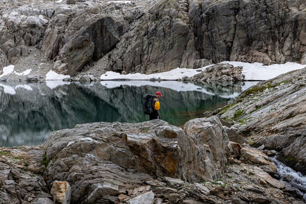 a man standing on top of a rock next to a lake