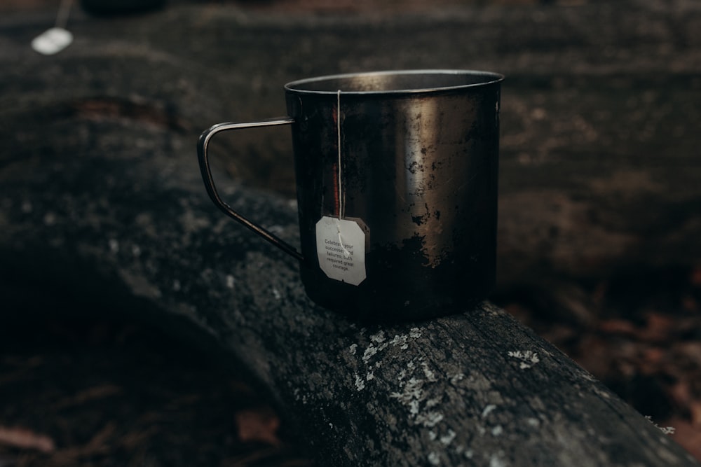 a metal cup sitting on top of a log